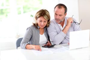 a man and woman sitting at a table looking at a laptop.