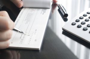 a person filling out a form next to a calculator.
